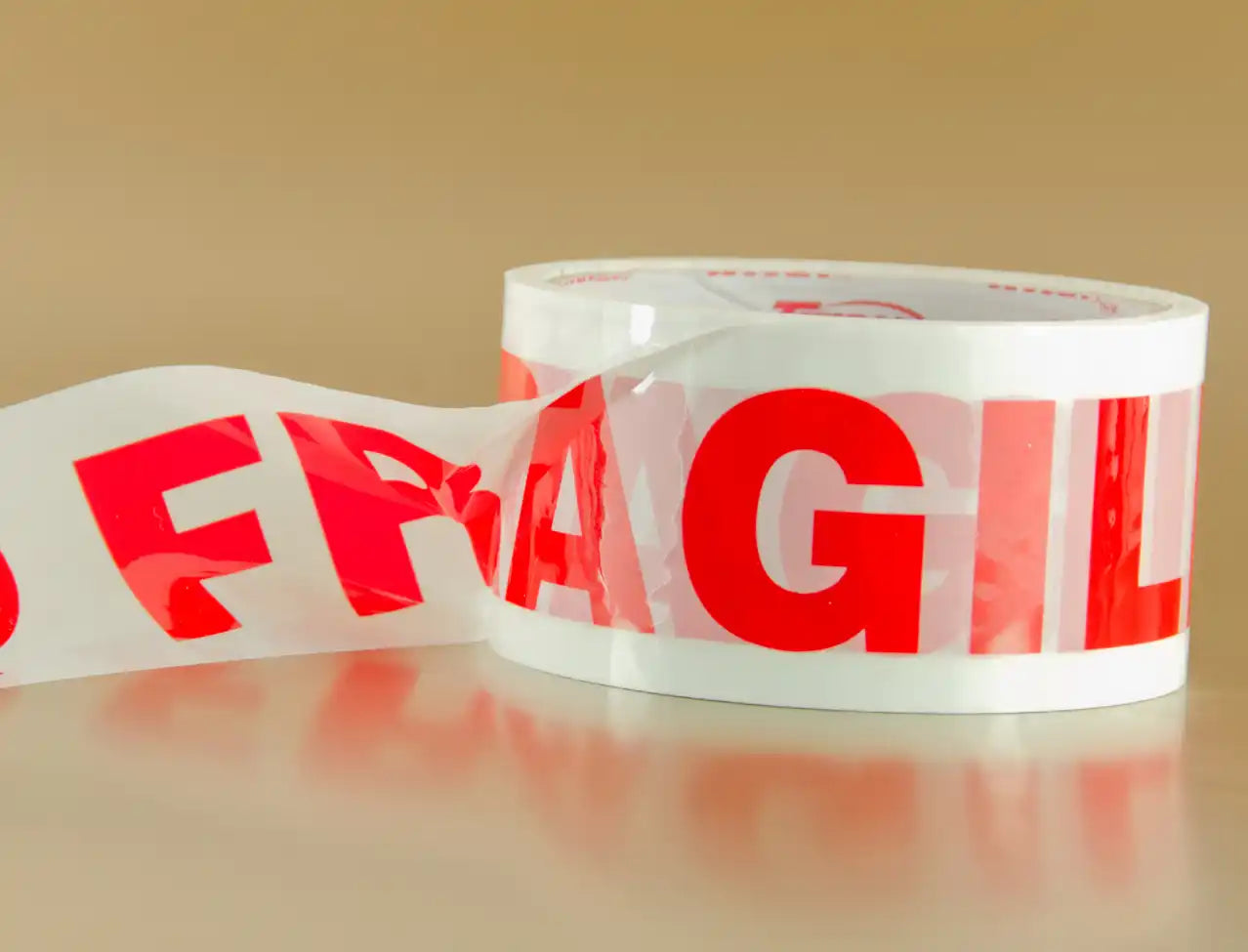 Clear packing tape with red ’FRAGILE’ text printed repeatedly on it.