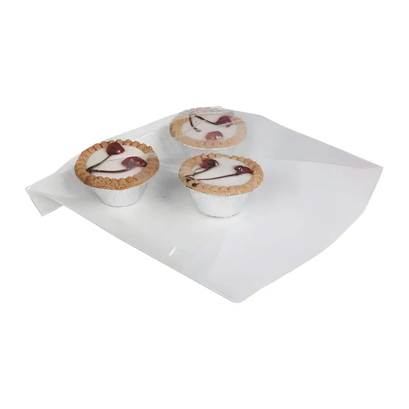 Three cupcakes with white frosting and cherries on film fronted paper bags UK