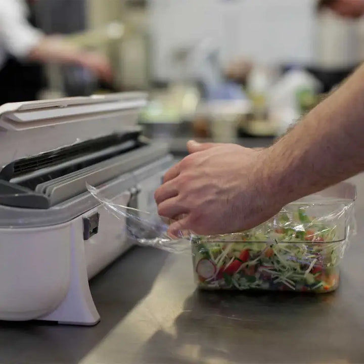 Food vacuum sealer with a hand reaching for salad beside Wrapmaster 4500 Cling Film Refill 45cm x 300m