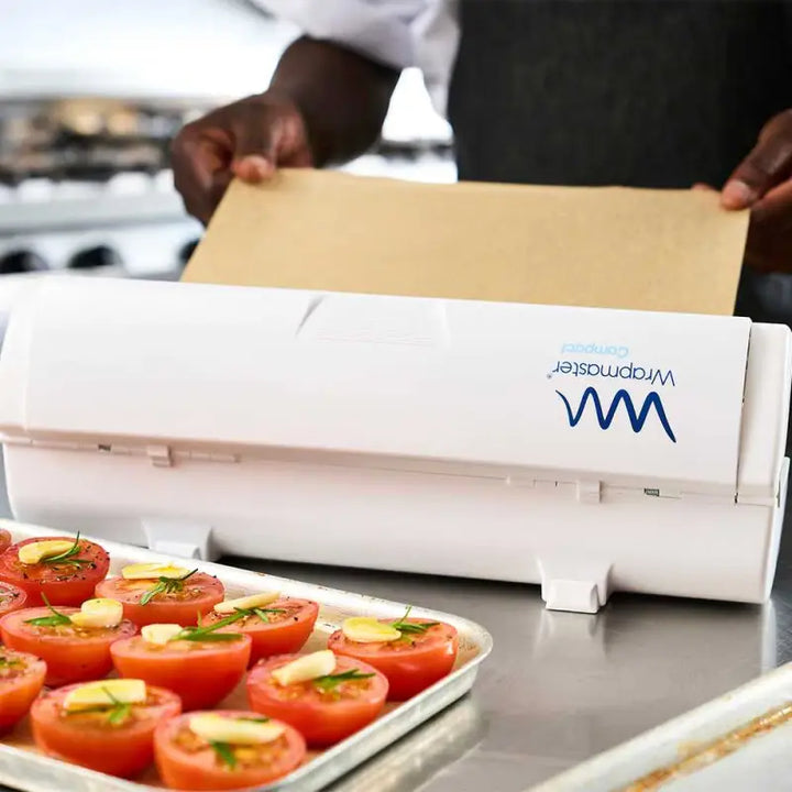 Vacuum sealer with VM logo near stuffed tomatoes and Wrapmaster Compact Baking Parchment