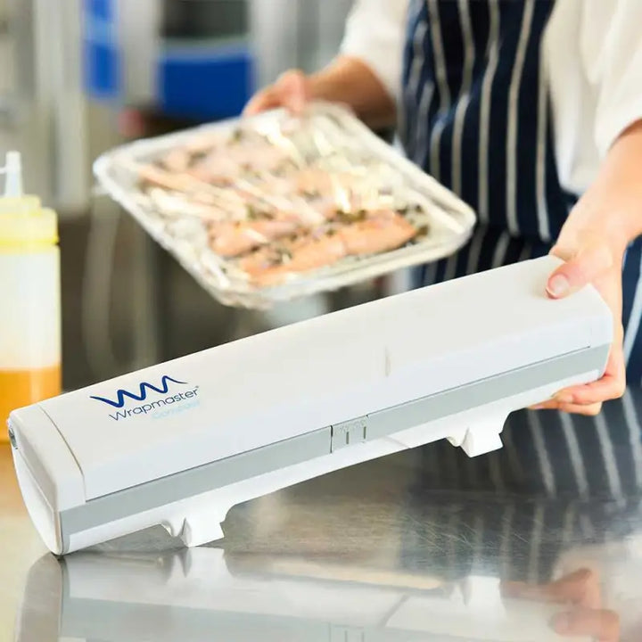 Plastic wrap dispenser with WM logo in kitchen, showcasing Wrapmaster Compact Dispenser